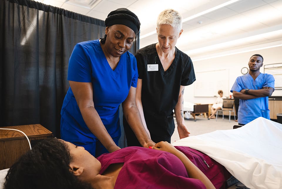 Woman learning how to treat a patient laying on a bed