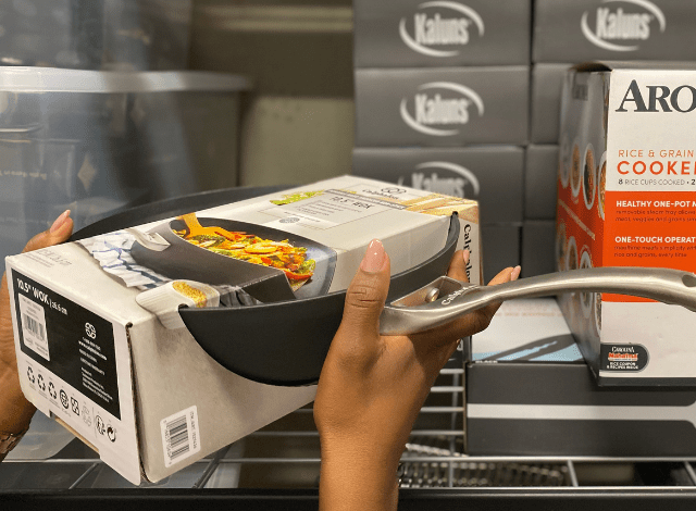 A woman's hand places a new pan on a shelf of donated housing supplies.