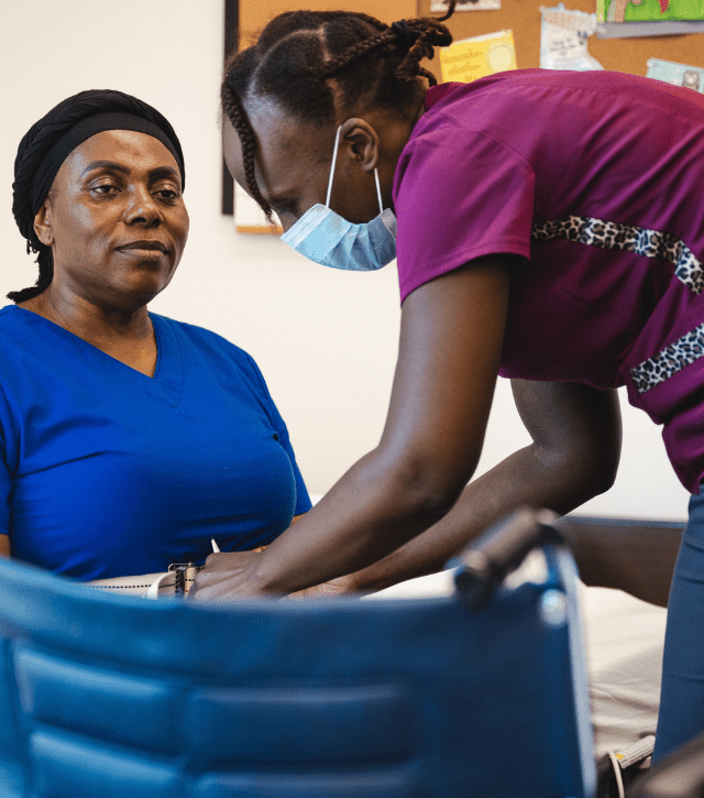 A nursing assistant training student practices skills with a student in a wheelchair.