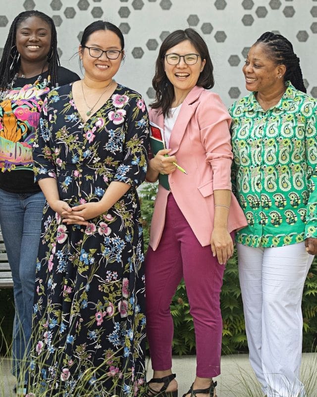 Four women of different ethnicities wear bright colors and smile.