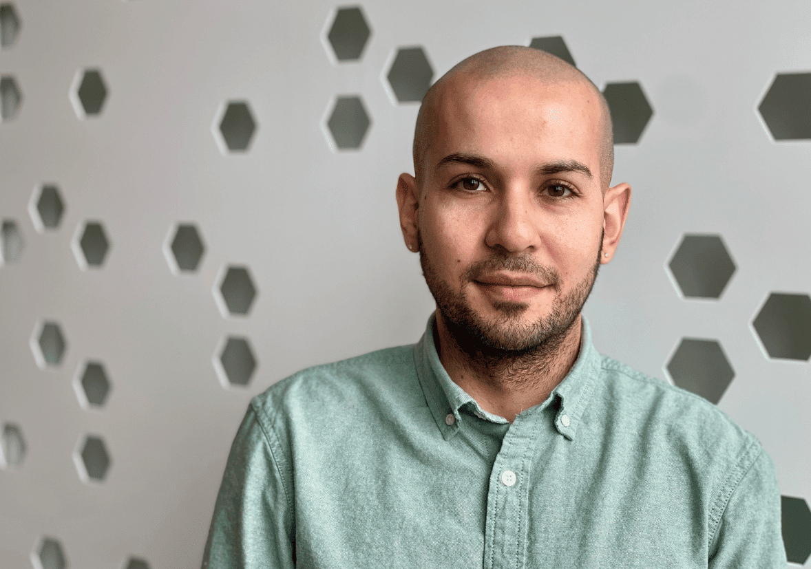 A man with a beard wearing a green button down shirt.